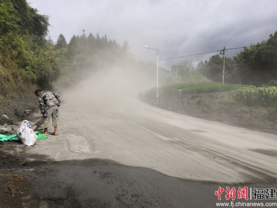 養(yǎng)路工帶上防塵口罩利用鐵鍬、竹掃把等工具清理灑落的水泥料。余思煥 攝